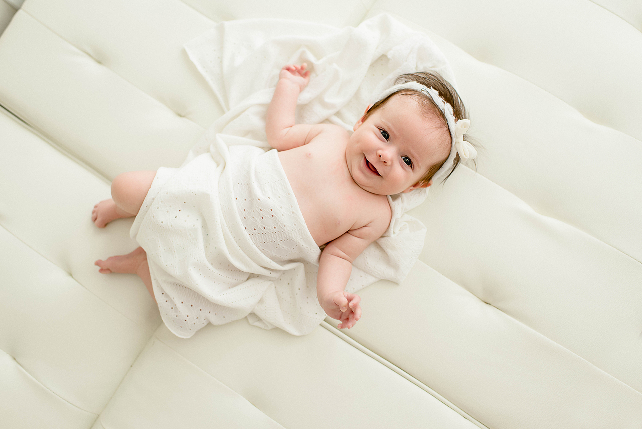 A newborn baby laughs while laying on a leather couch wrapped in a blanket lactation consultant jacksonville fl