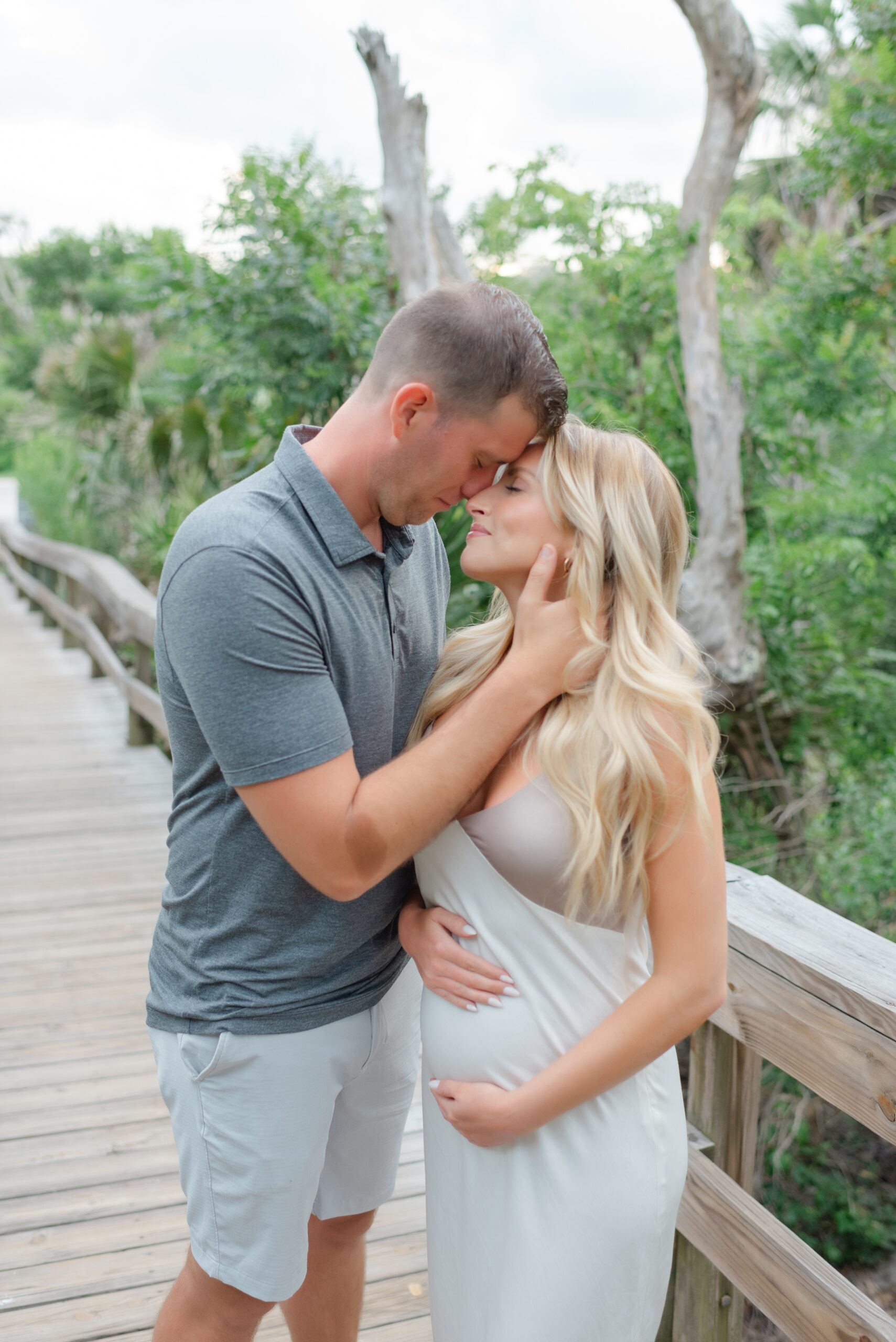 A happy expecting couple shares and intimate moment on a boardwalk