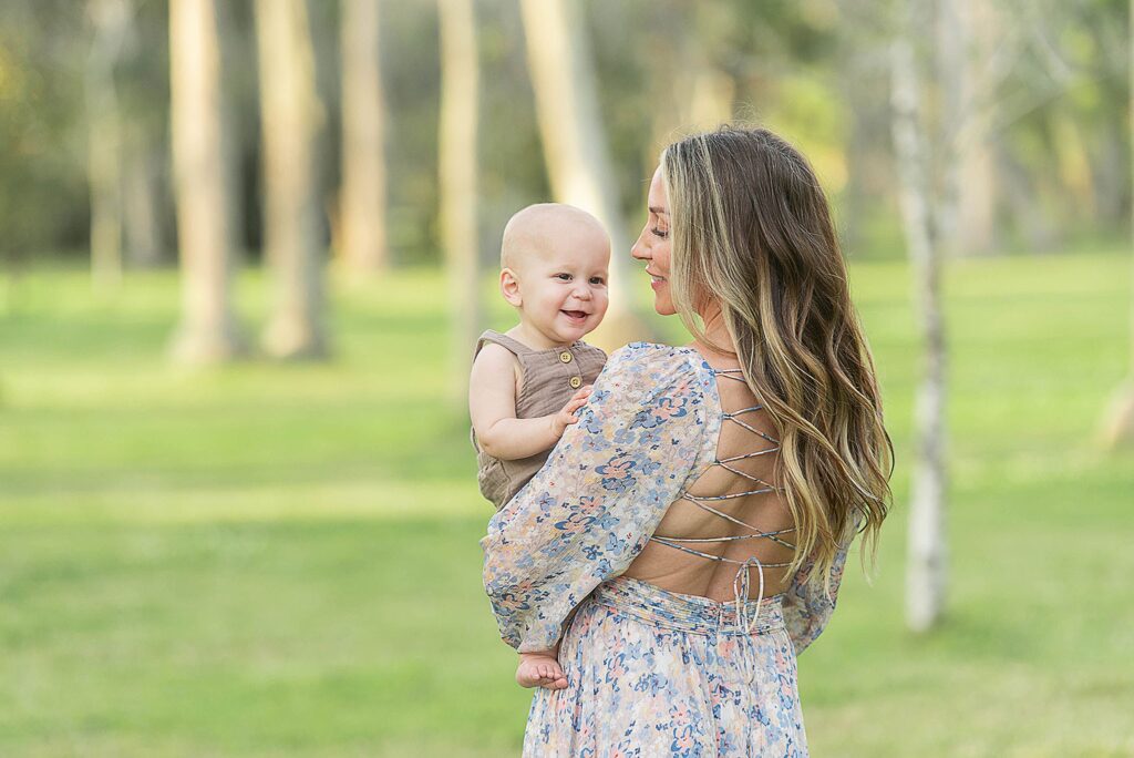 A happy infant sits in mom's arms in a park at sunset after some mommy and me classes jacksonville fl