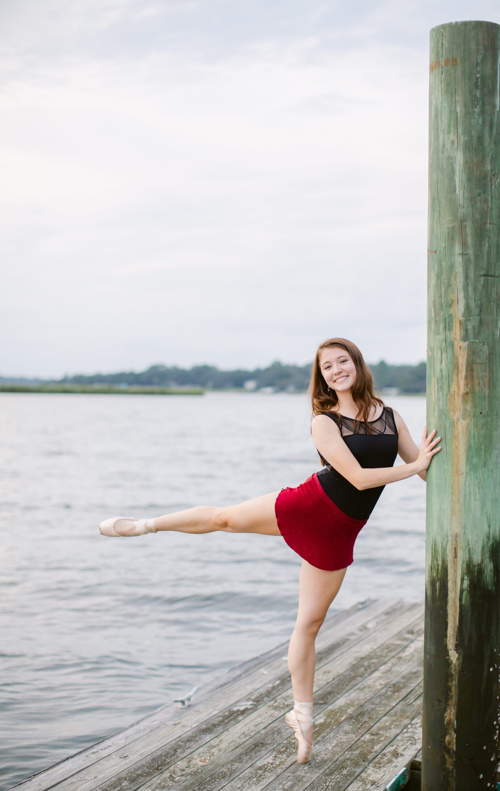 Girl on dock wearing pointe shoes in an arabesque position