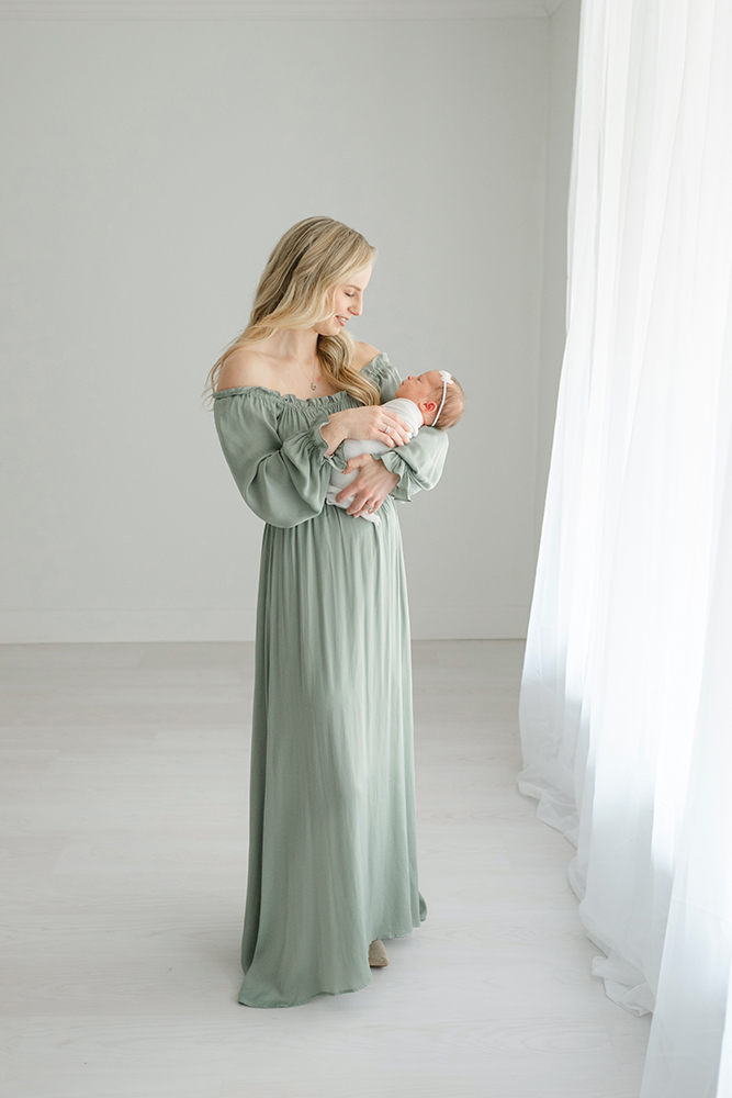 mom in off the shoulder green silk dress snuggling her baby girl