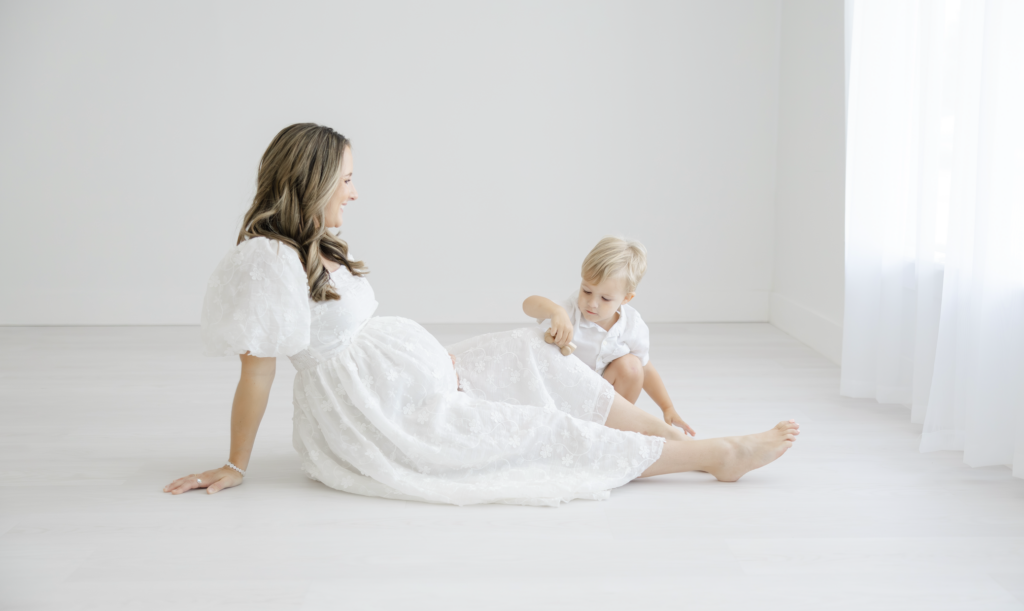 Studio maternity photographer featuring pregnant woman sitting on floor with toddler